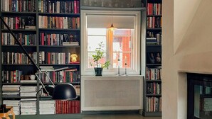 Un salon avec une cheminée, une bibliothèque, une fenêtre donnant sur un beau paysage et une table basse agrémentée de bougies.