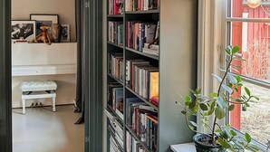 Une pièce avec une bibliothèque, un banc blanc et une plante en pot près d’une fenêtre.