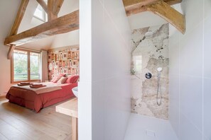 Ein Schlafzimmer mit einem großen Bett, Holzboden und einem Badezimmer mit Dusche.