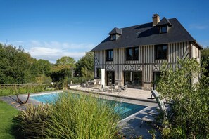 Ein zweistöckiges Haus mit Swimmingpool, Gartenmöbeln und einem Garten.