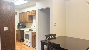 Una cocina con armarios de madera, microondas, estufa y una mesa de comedor con sillas.