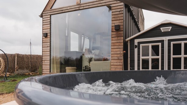 A modern house with a large glass window, a hot tub, and a wooden deck. - Maple Cottage - Tiny House with private spa (Profondeville)