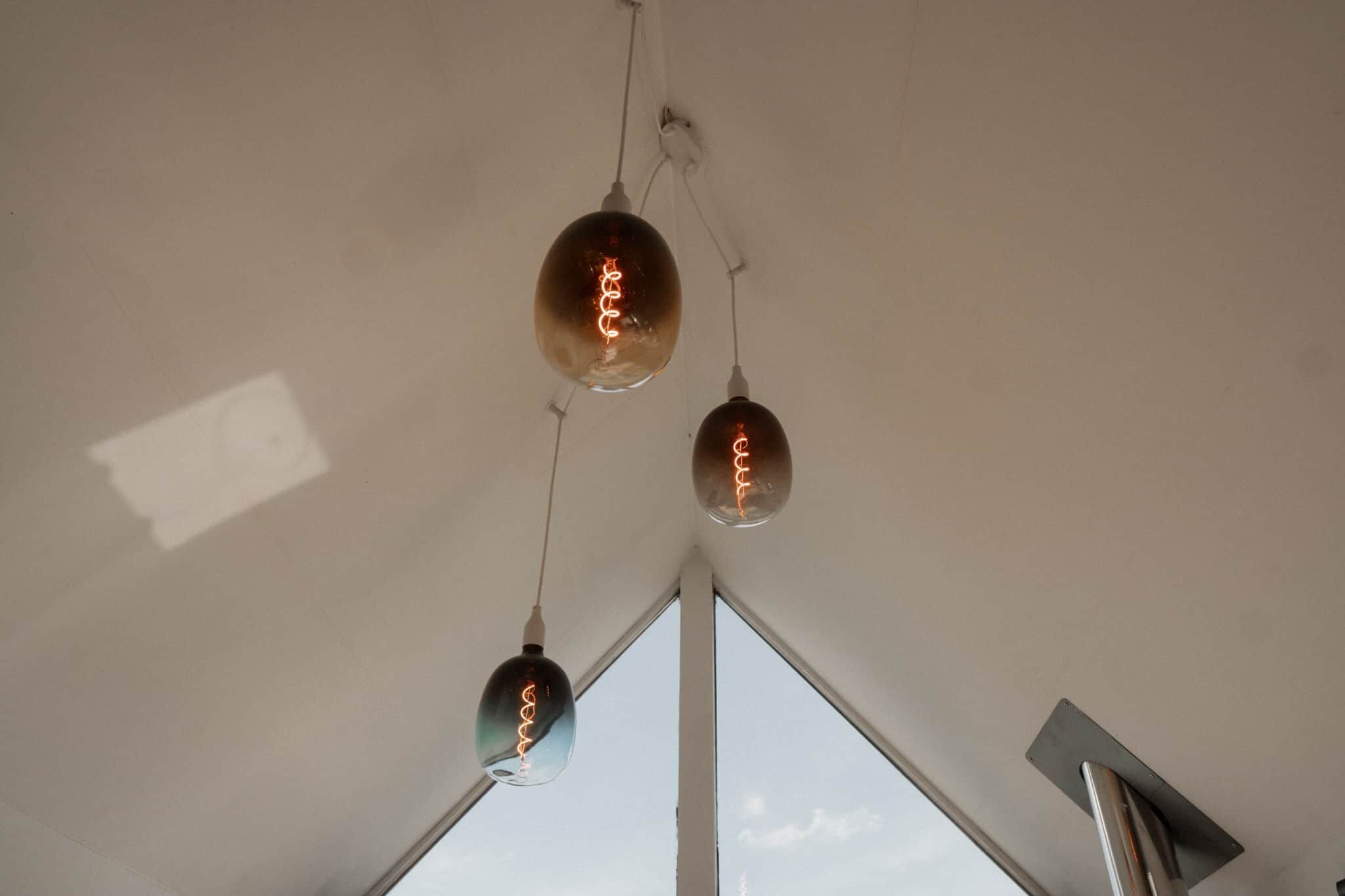 Une pièce dotée d’un plafond en pente et de trois suspensions lumineuses.