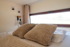 Un llit amb dos almoiners, una làmpada de nit i una finestra amb cortines.