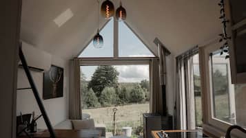 Eine moderne Küche mit einem großen Fenster, einem Essbereich mit Tisch und Stühlen und Blick auf eine grüne Landschaft.
