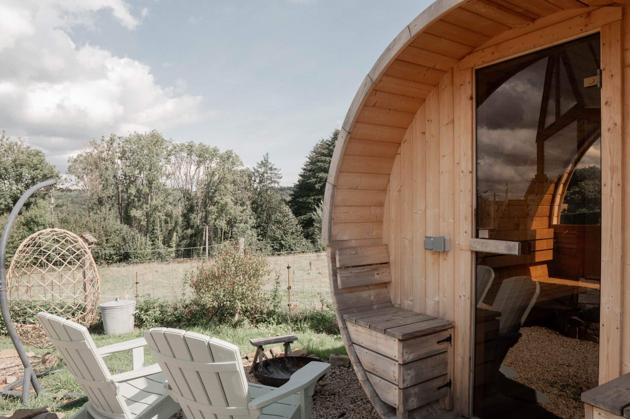 Een houten blokhut met een rond ontwerp, een eethoek met stoelen en een tafel, en uitzicht op het omliggende bos.