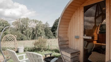 Een houten blokhut met een rond ontwerp, een eethoek met stoelen en een tafel, en uitzicht op het omliggende bos.