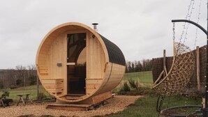 A wooden barrel-shaped structure with a door, a chimney, and a hanging swing. - Maple Cottage - Tiny House with private spa (Profondeville)