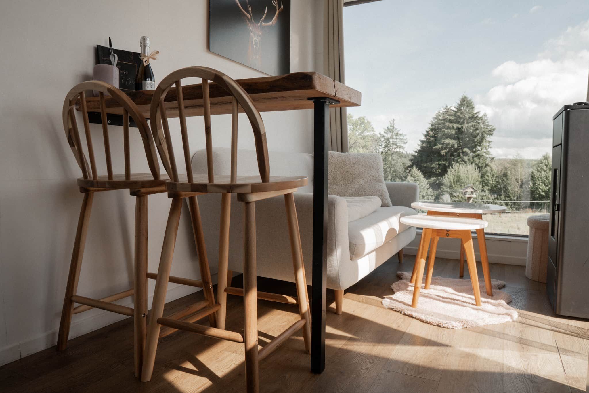 A modern living room with a wooden table, two chairs, a sofa, and a small round table.