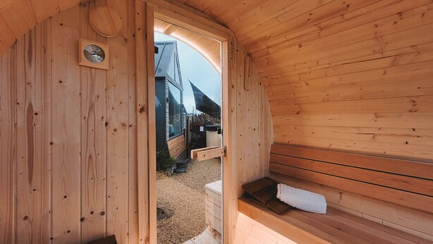 Una sauna de fusta amb una barra, una porta que dona a l'exterior i una paret de fusta amb una brúixola.