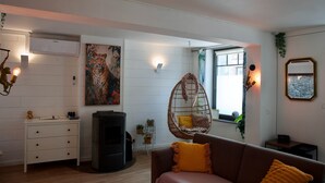 A living room with a sofa, a hanging chair, a fireplace, and a painting on the wall. - Costa Rica - Tropical immersion (Profondeville)