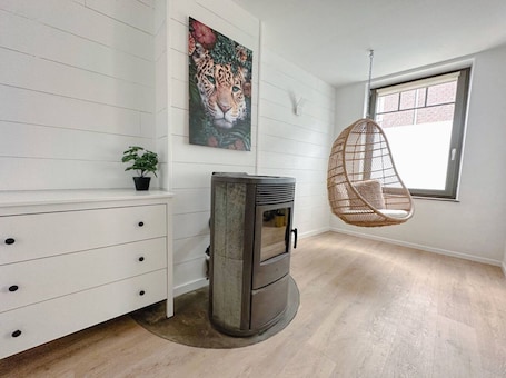 A room with a white wall, a painting of a leopard, a hanging chair, a wood-burning stove, and a window.. Costa Rica - Tropical immersion