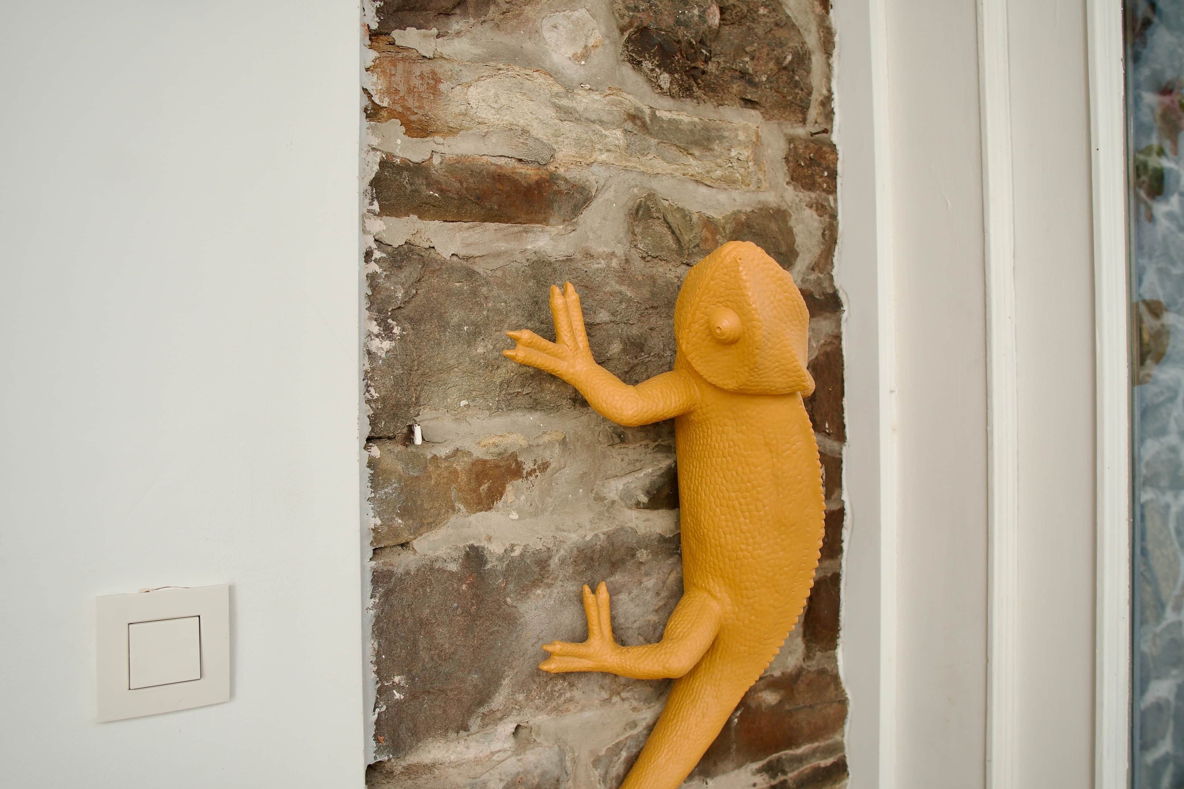 Scultura di un lucertola su un muro strutturato.