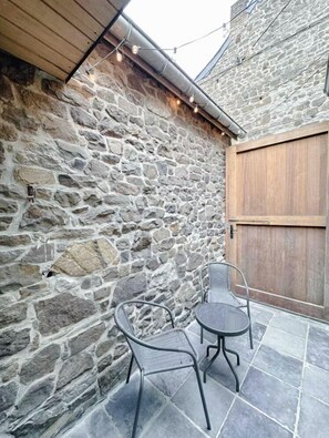 A stone wall, a wooden door, and two metal chairs on a tiled patio. - Costa Rica - Tropical immersion (Profondeville)
