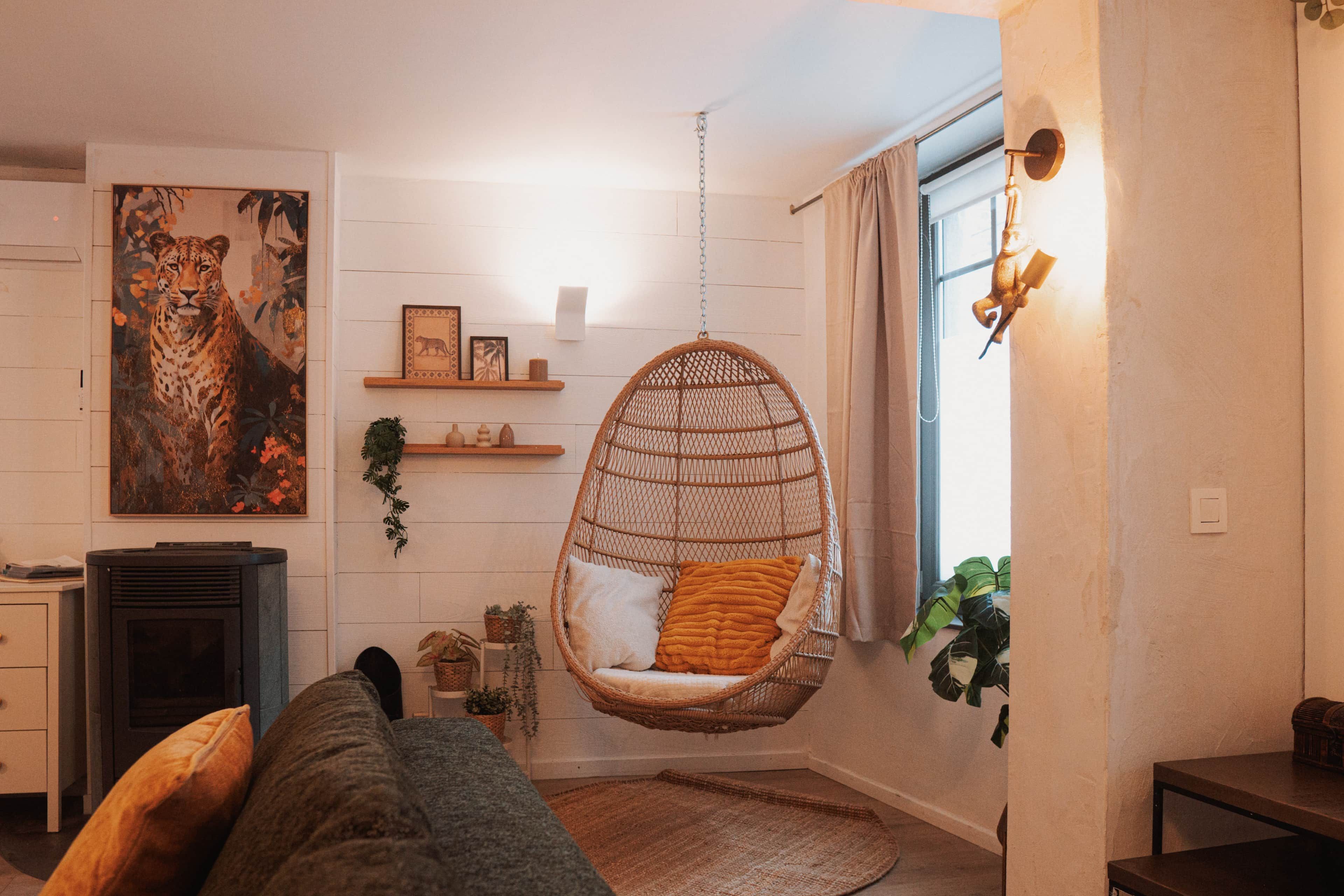 A cozy living room with a hanging chair, a sofa, a fireplace, and a large painting of a leopard.