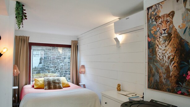 A bedroom with a bed, a desk, a treadmill, a stone wall, and a painting of a leopard. - Costa Rica - Tropical immersion (Profondeville)
