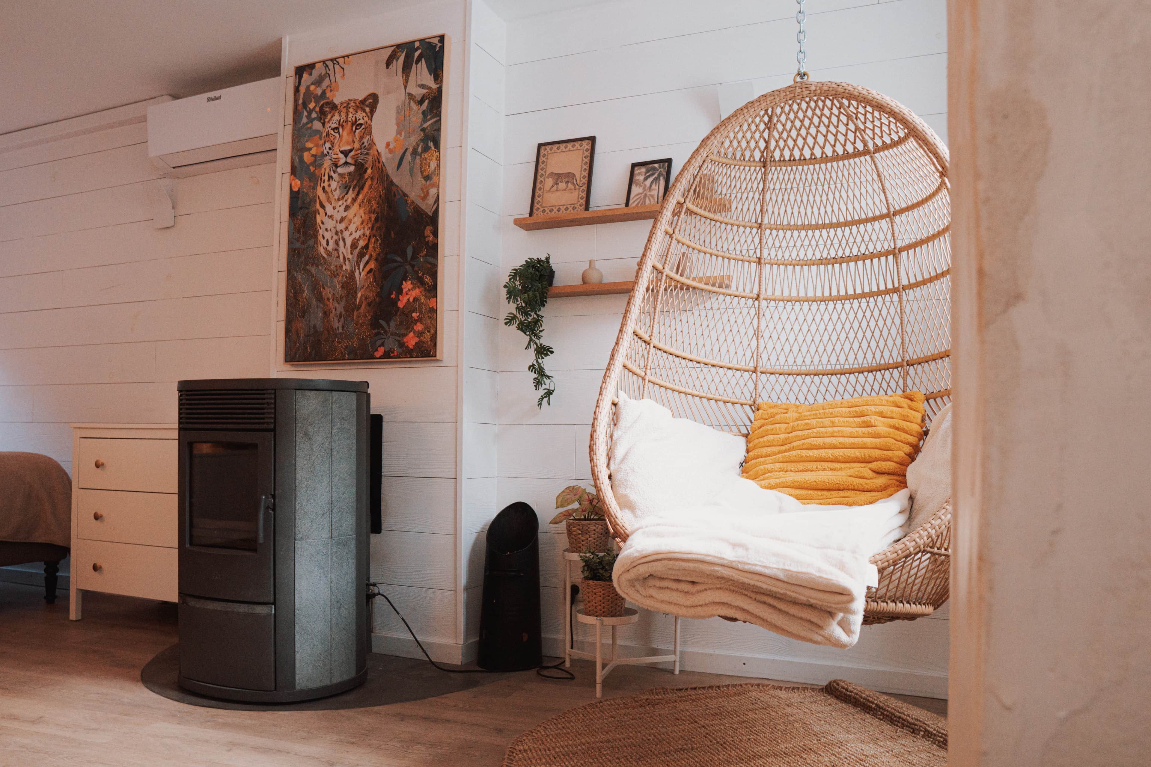 A cozy room with a hanging chair, a fireplace, and a large painting.