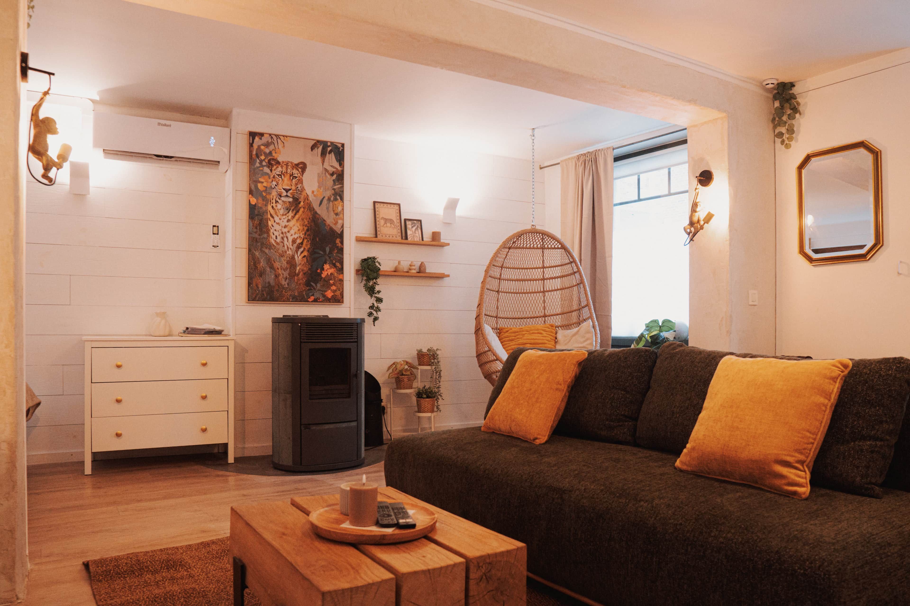 A living room with a sofa, a hanging chair, a fireplace, and a painting of a leopard.