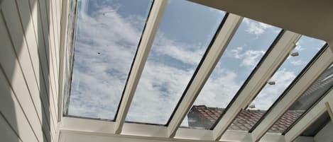 Un tragaluz con vistas al cielo y un edificio con tejados de tejas rojas.