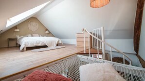 A bedroom with a sloped ceiling, a bed, a staircase, and a hanging light fixture. - Le Bali - Zen & serenity (Profondeville)