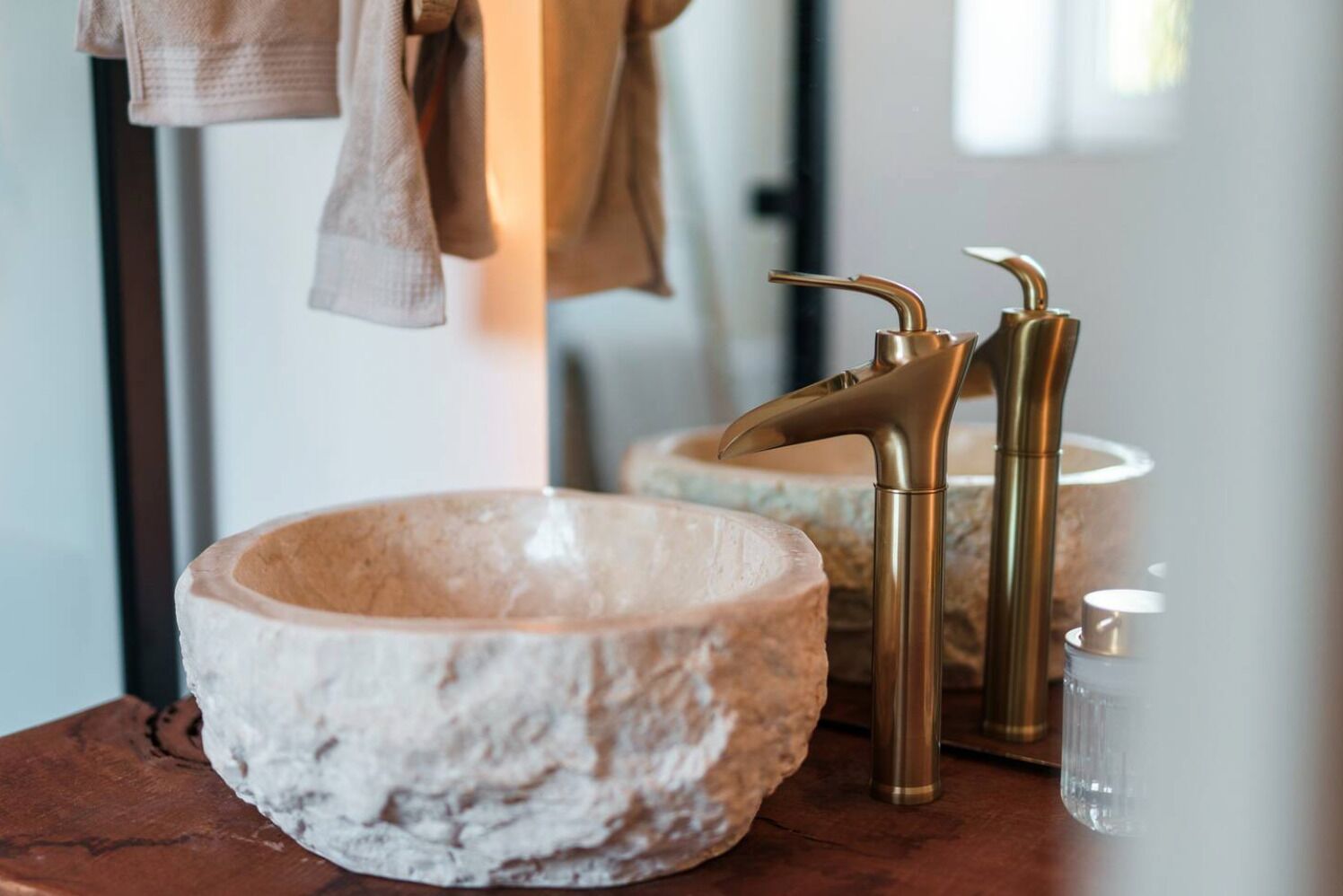 Une salle de bain avec un lavabo en pierre, des robinets dorés et un miroir.