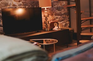 A cozy room with a television, a lamp, a radio, and a bed.