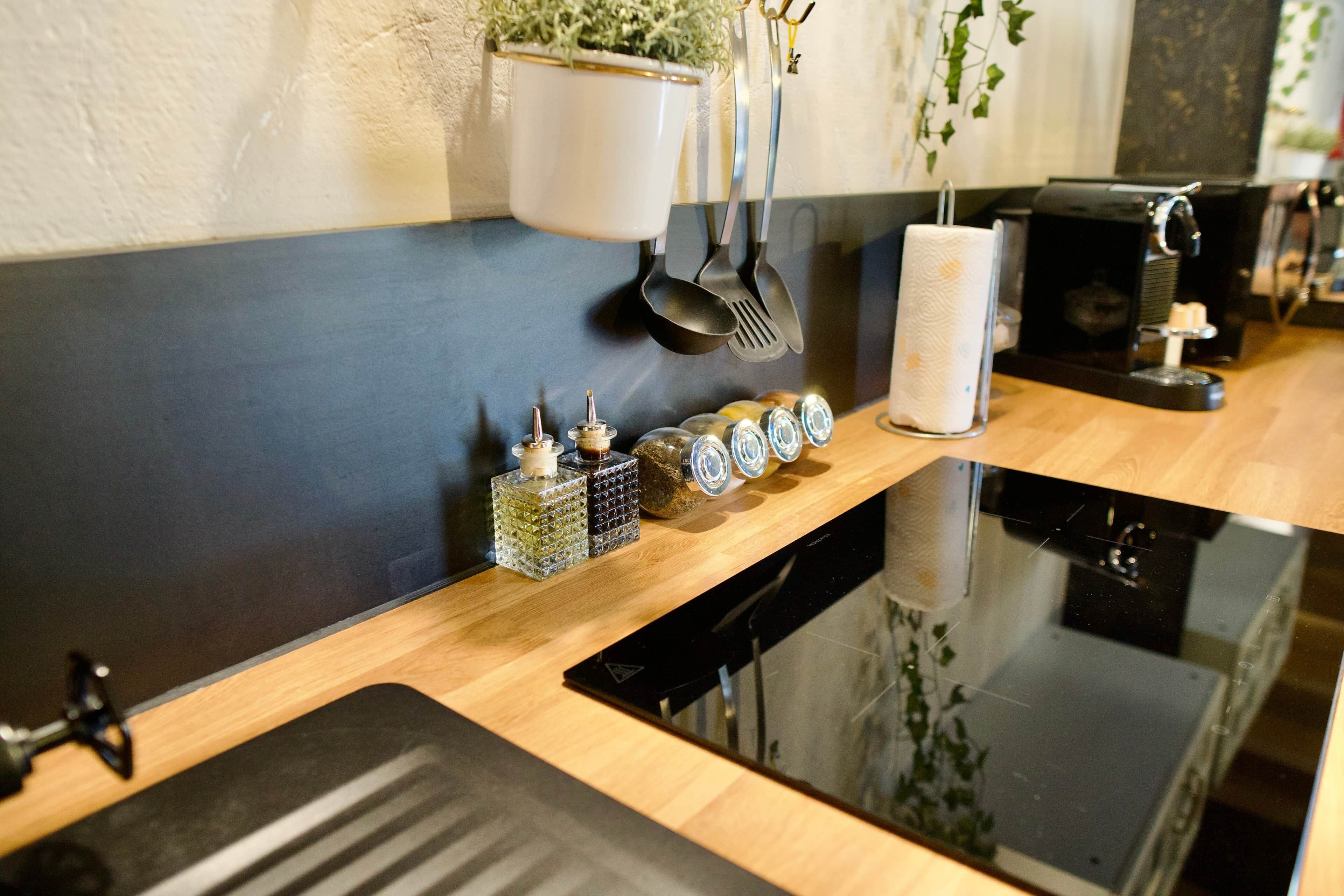 Una cocina con encimera negra, una cafetera y diversos utensilios de cocina.