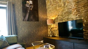 Una sala de estar moderna con pared de piedra, un televisor de pantalla plana, una lámpara y una mesa de centro de vidrio.