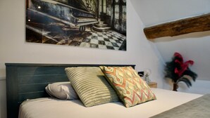 Una cama con cabecera, dos almohadas y un cojín decorativo con estampado geométrico.