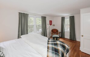 A bedroom with a bed, a chair, a reading lamp, and a sign that says 'READ MORE BOOKS'. - Dam Good Times - 90s Lake Getaway (Stoddard)