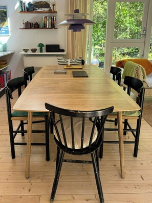 A dining area with a long wooden table, black chairs, and a hanging pendant light. - Forest house near Bakka Harbor and Kadeau (Aakirkeby)