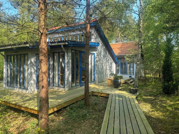 A cabin with a deck, a large window, and a door.