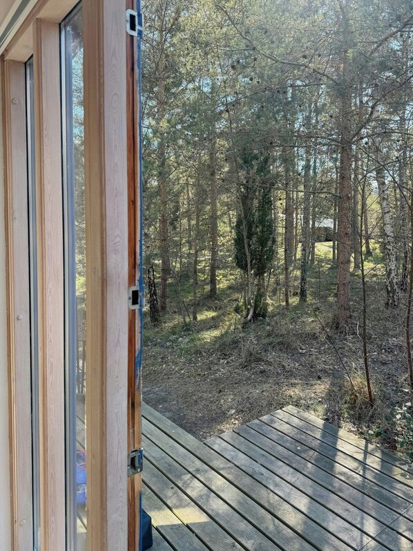 Puinen terassi, joka johtaa metsäiselle alueelle, ja lasiovesta avautuu näkymä.