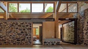 Ein modernes Interieur mit Steinsäulen, Holzbalken und großen Fenstern.