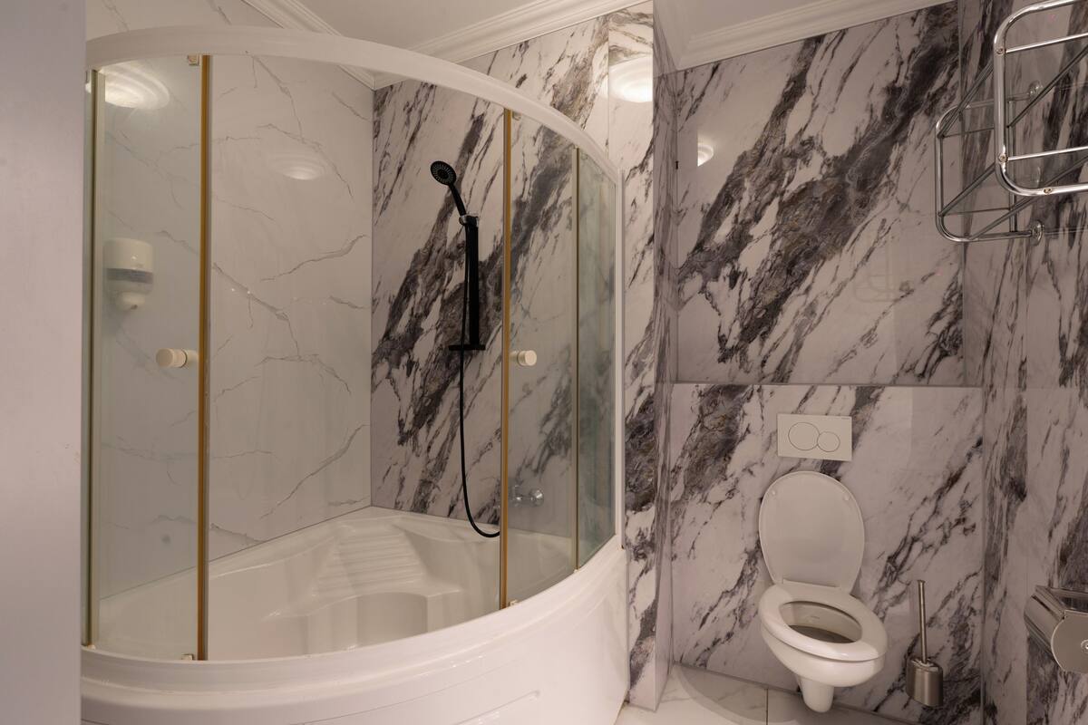 Un baño con ducha de vidrio, una bañera blanca y un inodoro.