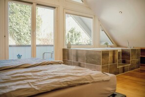 Ein Schlafzimmer mit einem großen Bett, einem Oberlicht und Blick auf Bäume.