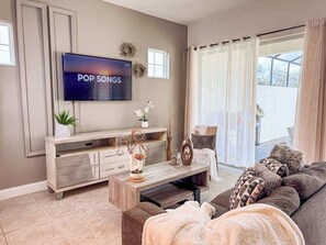 Ein Wohnzimmer mit Fernseher, Sofa, Couchtisch und Dekorationselementen.