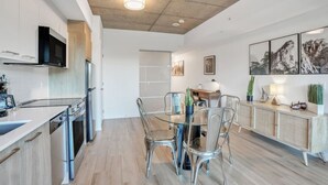 Una cocina moderna con comedor, que incluye una mesa y sillas de vidrio, horno empotrado y microondas.