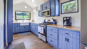 A kitchen with blue cabinets, a microwave, a stove, and a coffee maker.