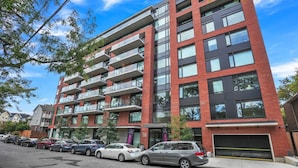 Un edificio residenziale a più piani con balconi, un garage e una fila di auto parcheggiate.