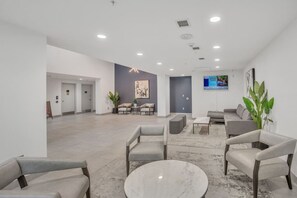 Eine großzügige Lobby mit einem Marmortisch, grauen Sofas und einem großen Gemälde an der Wand.