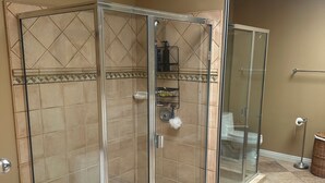 Ein Badezimmer mit einer Duschkabine, einer Toilette und einem Mülleimer.