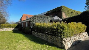 Ein Haus mit einer Steinsäule, einem roten Dach und einem Garten.