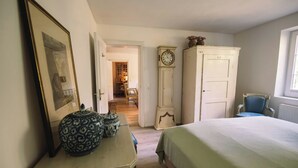 Ein Schlafzimmer mit einem Bett, einem Schminktisch, einer Uhr und einem Sessel.