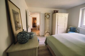 A bedroom with a bed, a dresser, a clock, and a chair.