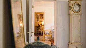 Ein Zimmer mit einem großen Spiegel, einer Uhr und einem Teekännchen auf einem Tisch.
