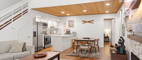 A modern living space with a kitchen, dining area, and a fireplace.