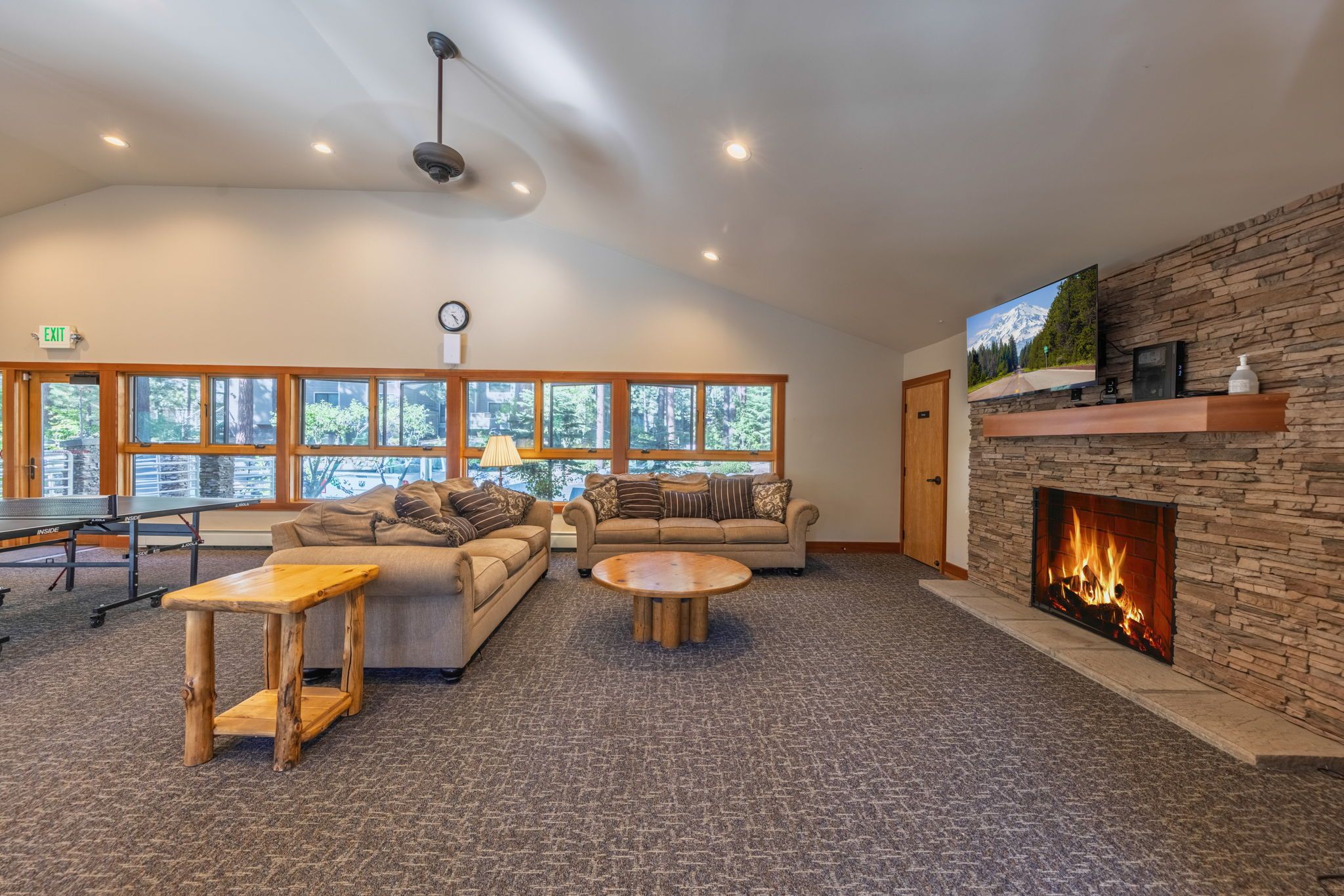 A spacious living room with a fireplace, a sofa, a coffee table, and a ping pong table.