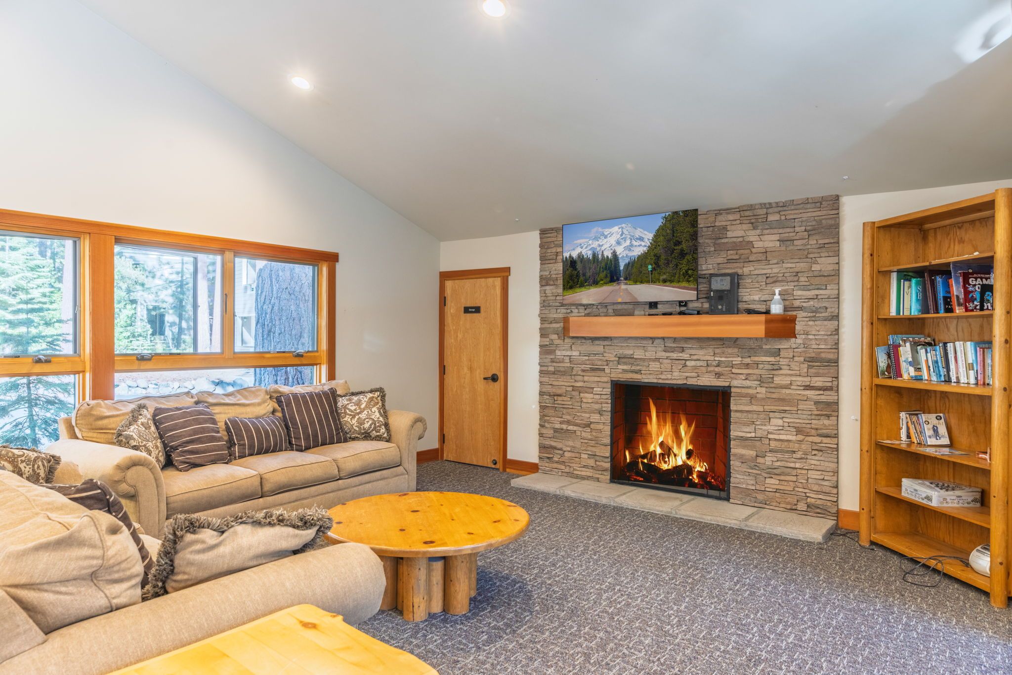 A living room with a stone fireplace, a sofa, a coffee table, and a bookshelf.