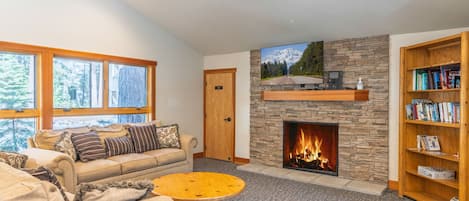 A living room with a stone fireplace, a sofa, a coffee table, and a bookshelf.